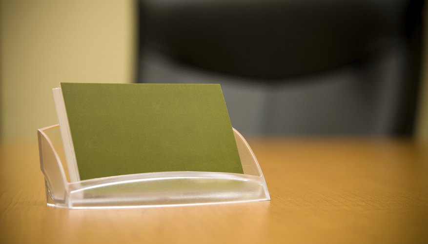 A business card holder is holding blank cards on a desk.