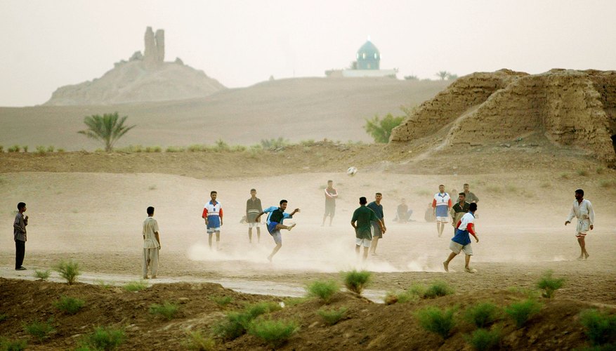 The ruins of a ziggurat built by Nebuchadnezzar rise in the distance behind an Iraqi soccer game.