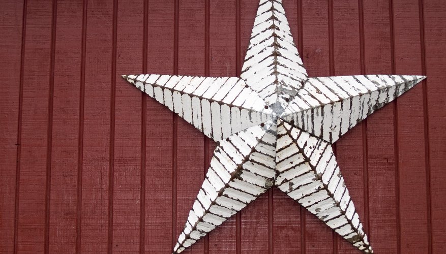 A close-up of a rustic metal star on the wall of a red barn.