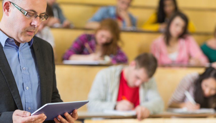 Professor looking at tablet in lecture hall.