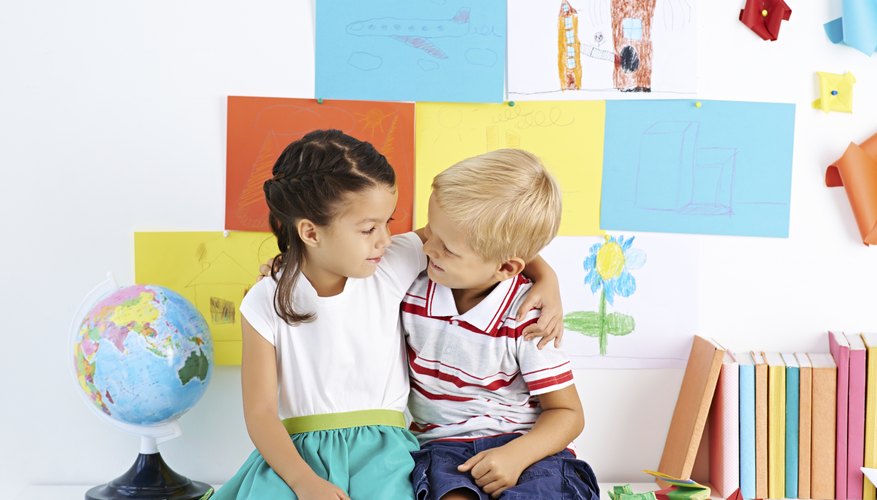 Young boy and girl student hugging in classroom