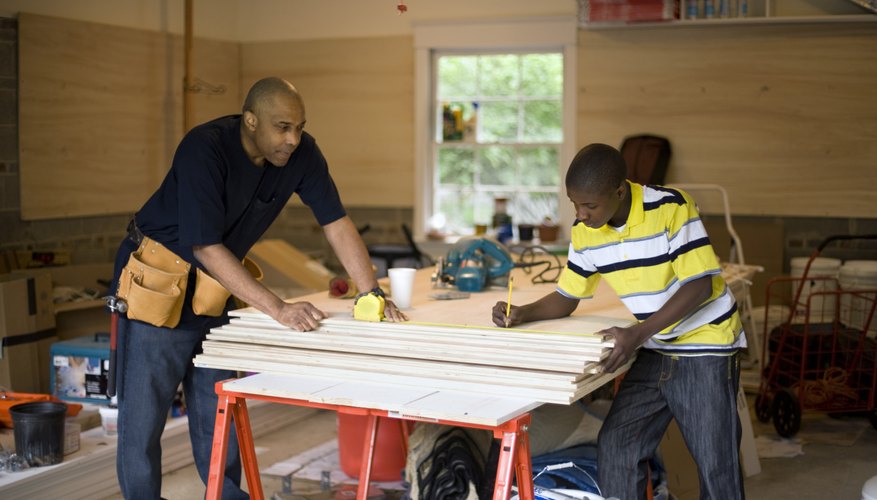 Two young kids and a man are doing woodworking together.