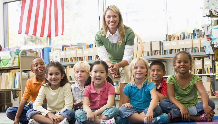 Elementary students sitting in front of American Flag