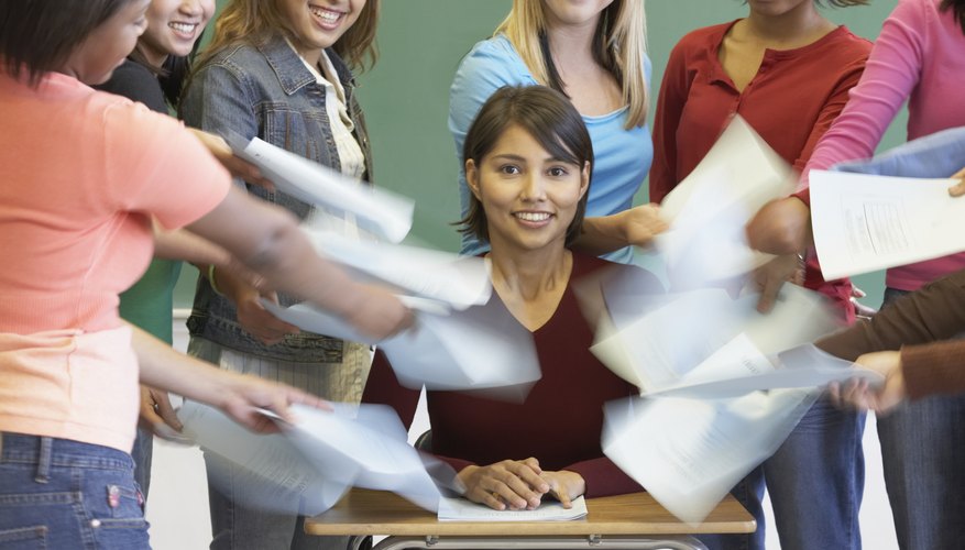 Students handing in papers to teacher at desk