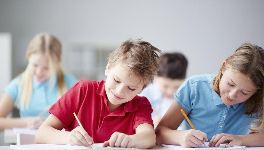 Two students writing in notebooks in elementary school.