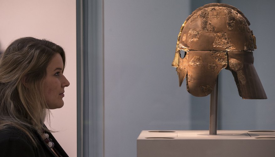 A woman looking at a medieval artifact in a museum.