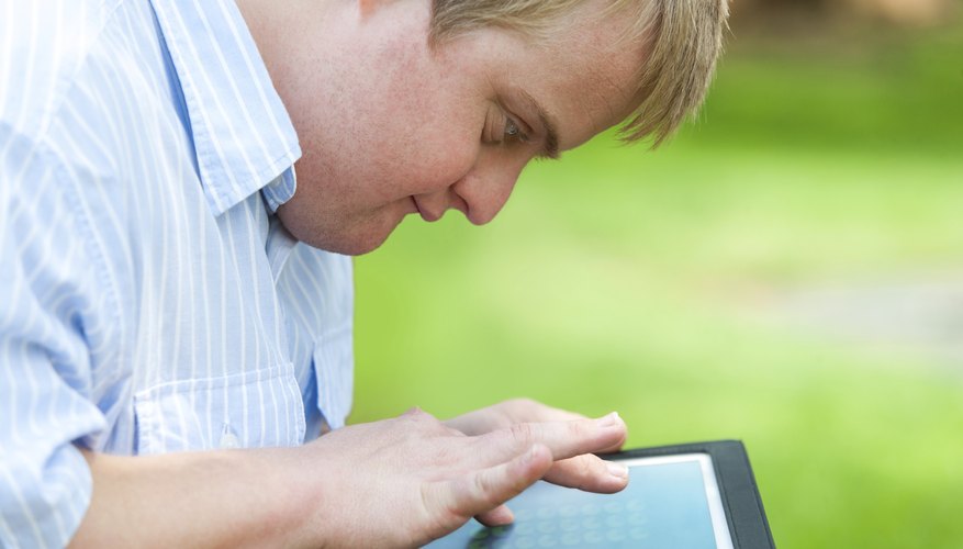 A boy with down syndrome is using a tablet.