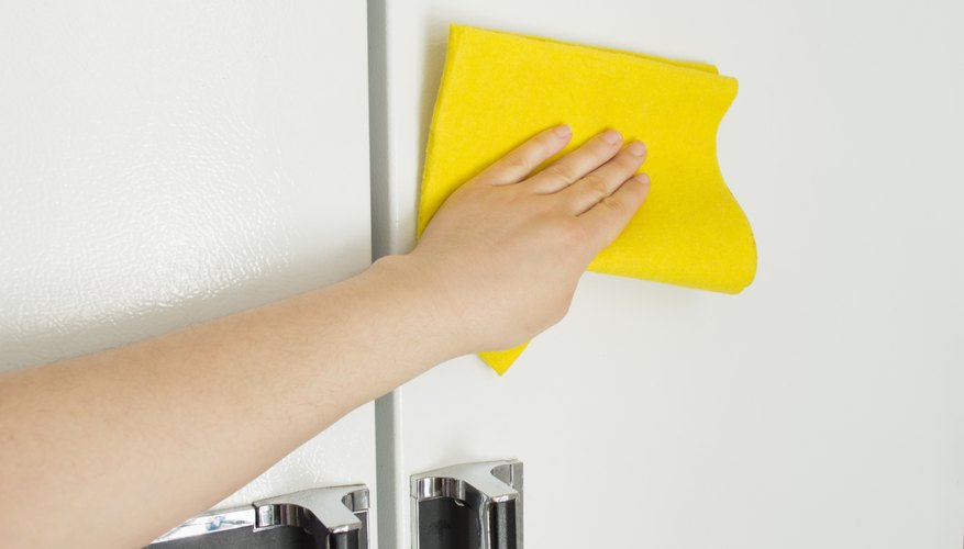 Hand wiping down refrigerator exterior
