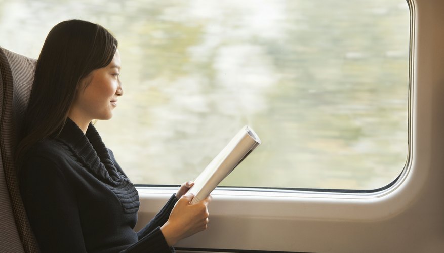 Student reading periodical on train.