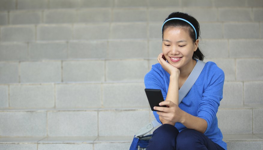 A student sits on stairs looking at her smart phone.
