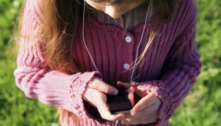 A girl listens to an mp3 player outside.