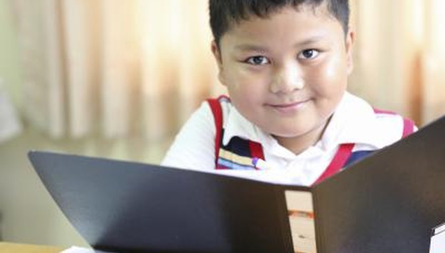 A school boy looks at documents in a binder.