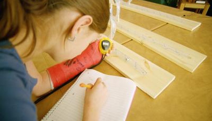 A girl holds a stop watch and writes on a piece of paper.