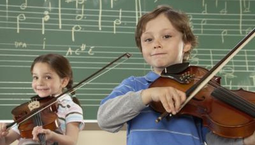 A boy and girl play violins in a music class.