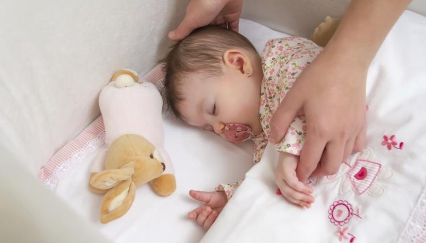 A baby with a pacifier sleeping in a crib. A baby with a pacifier sleeping in a crib.