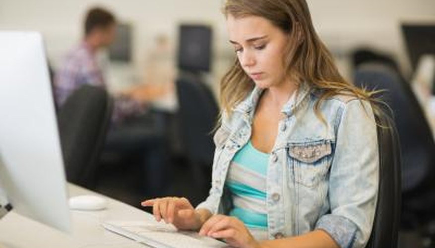 High school student typing on computer in library