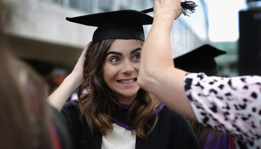 A mother adjusts her daughter's cap at a college graduation.