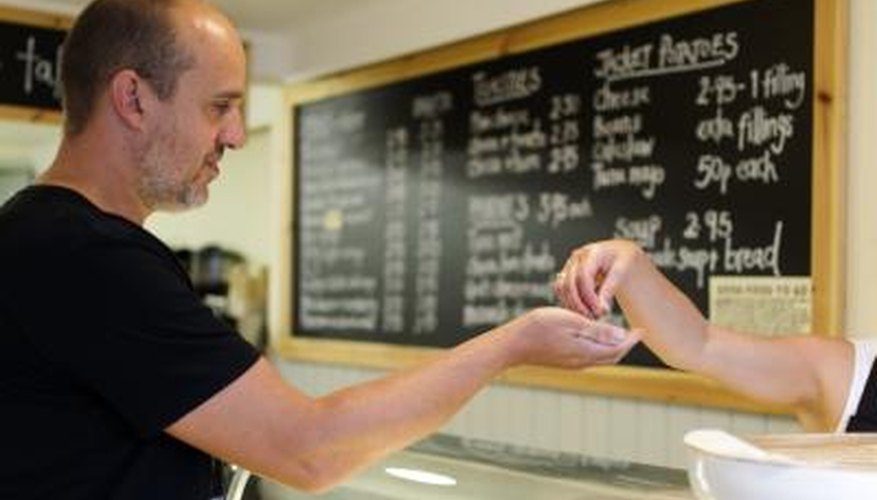 Photo Credit: Mypurgatoryyears/iStock/Getty Images A customer and employee exchange money over a counter.