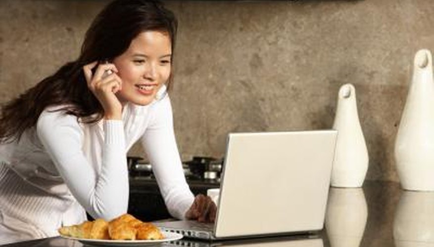 Woman making phone call while researching on laptop.