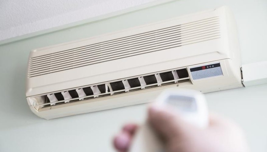 Close-up of hand using remote to turn on air conditioner. Close-up of hand using remote to turn on air conditioner.