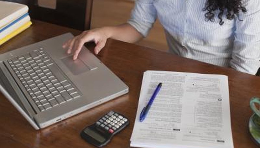 Photo Credit: FogStock/Erik Palmer/FogStock/Getty Images A woman fils out tax documents at a desk.