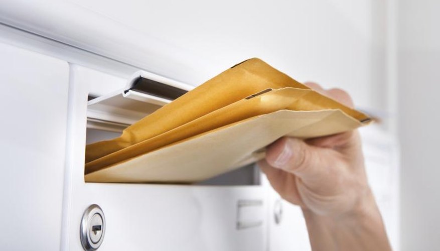 A man is pulling letters from a mailbox.