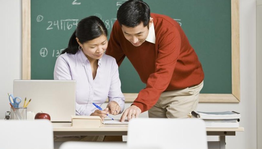 Student showing teacher paperwork at her desk