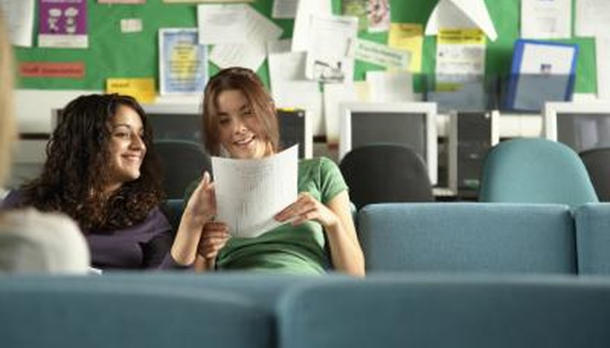 High school students looking at paper in classroom.