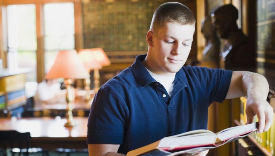 College student reading book in library.