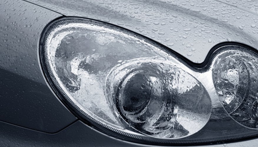 Shiny car with silver paint. Water drops on the hood. Car lamp.