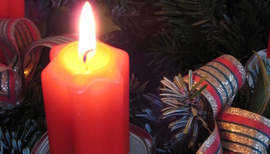 Distintas personas usan velas de diferentes colores para adornar las coronas de Adviento.