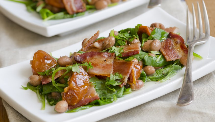 Two spinach salads topped with garbanzo beans and bacon. Two spinach salads topped with garbanzo beans and bacon.