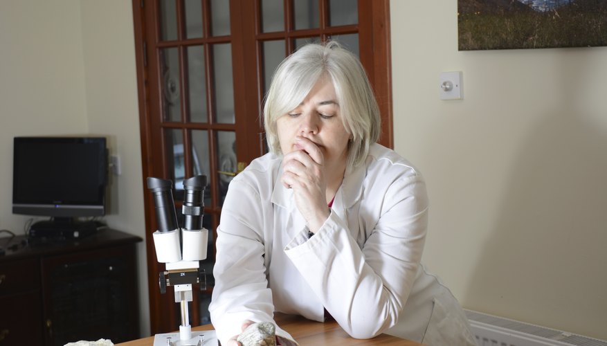 Photo Credit: Siobhan_Fraser/iStock/Getty Images A scientist examining rocks with a microscope.