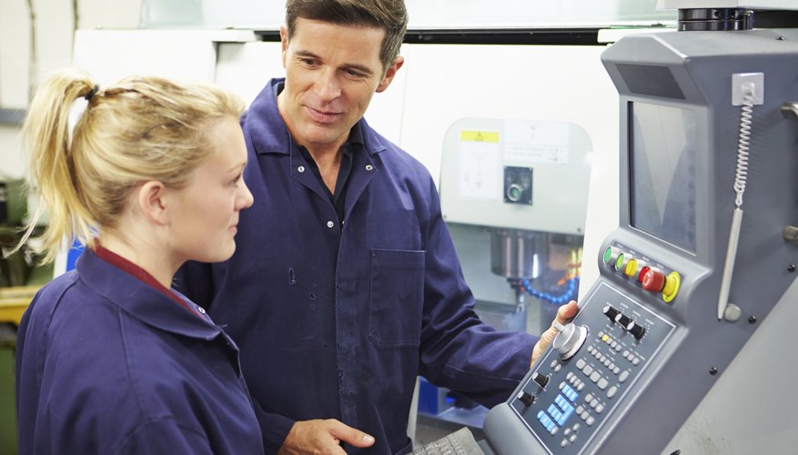 Engineer And Apprentice Using Automated Milling Machine