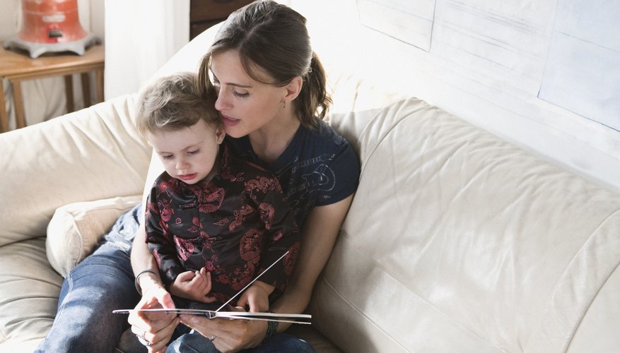 A mother reading a book to her toddler on the sofa. A mother reading a book to her toddler on the sofa.