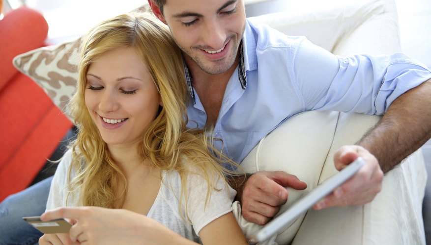 Photo Credit: Goodluz/iStock/Getty Images A couple shops online at home on the couch with a tablet computer.