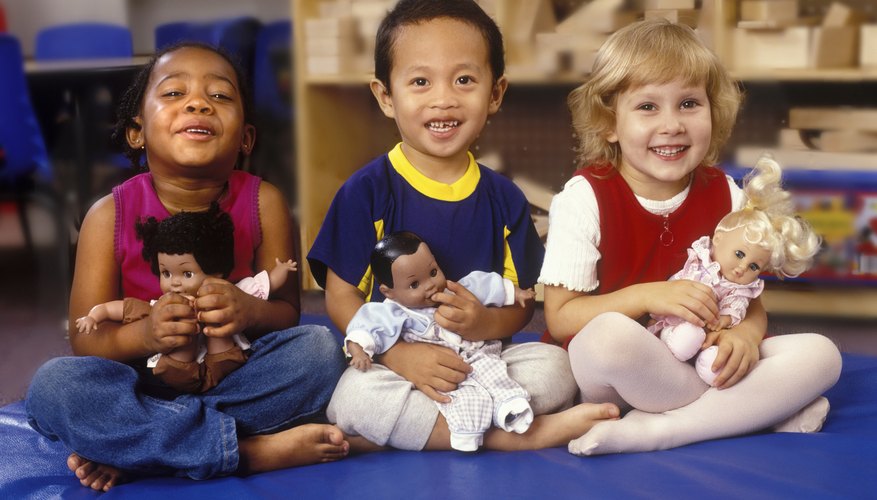 Three young children playing on mats with dolls. Three young children playing on mats with dolls.