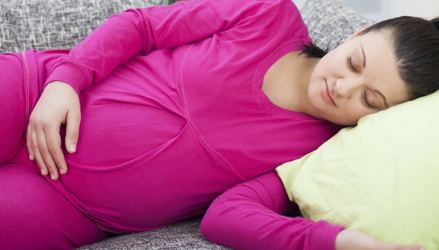 A pregnant woman taking a nap on the couch. A pregnant woman taking a nap on the couch.