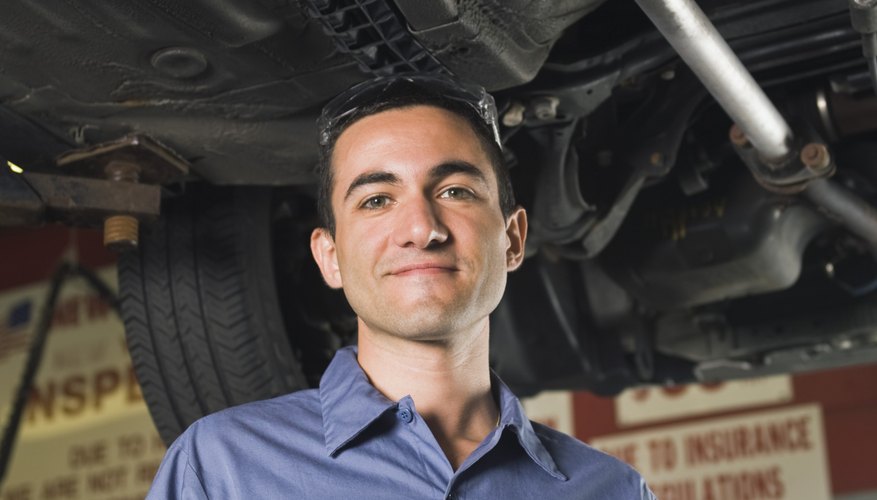 Smiling mechanic underneath car