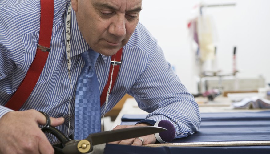 A tailor cuts fabric with a pair of scissors A tailor cuts fabric with a pair of scissors