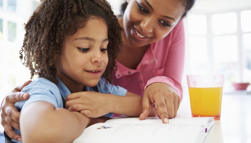 Mother helping child with homework at table Mother helping child with homework at table