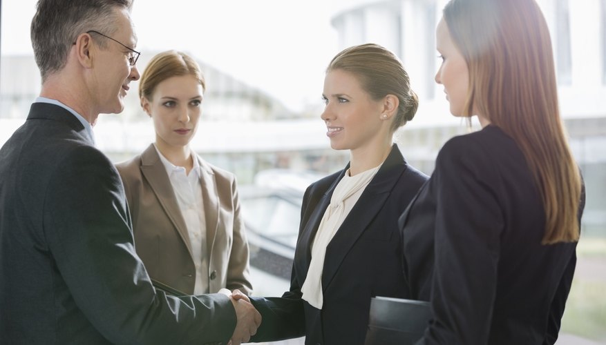 Confident business people shaking hands at workplace