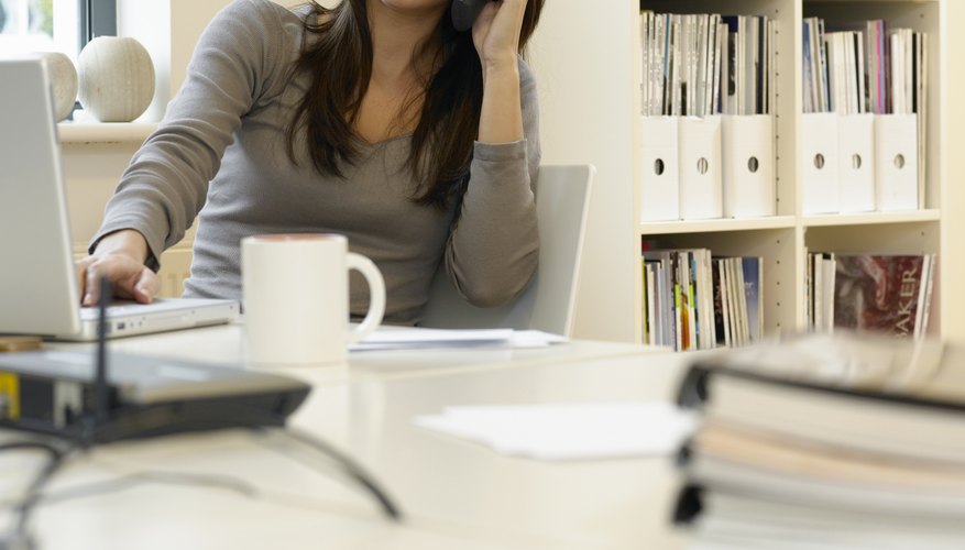 Woman at desk in office using mobile phone, smiling