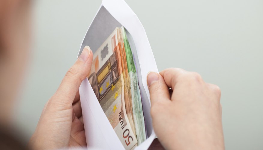 A woman opening an envelope filled with cash.
