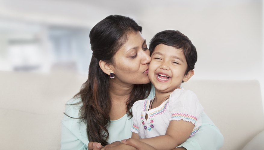 Mother kissing young daughter on the cheek.