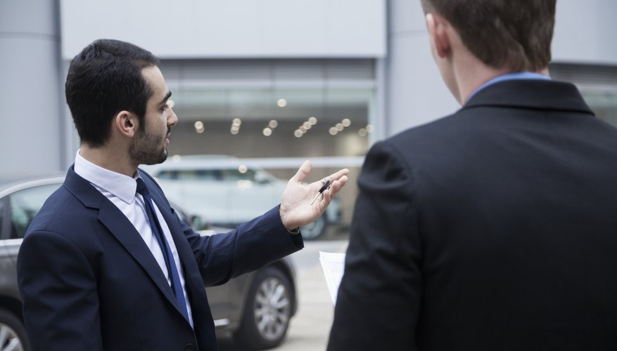 Car salesman holding the keys to a new car