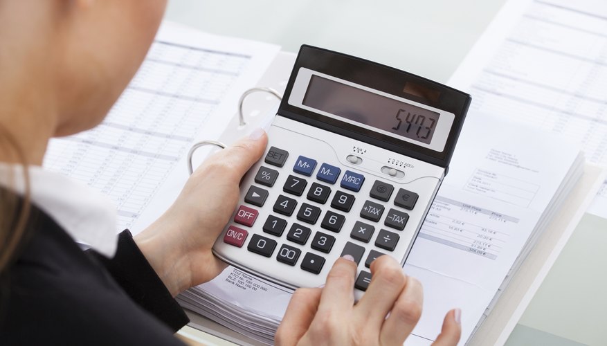 Woman using a calculator while working on her taxes.