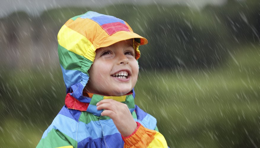 Young child in raincoat smiling as rain falls Young child in raincoat smiling as rain falls