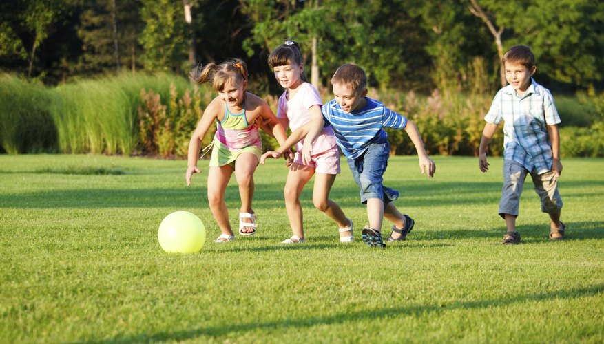 Four young children playing soccer on grass field Four young children playing soccer on grass field