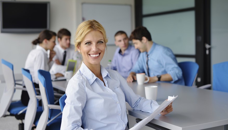 business woman with her staff in background at office